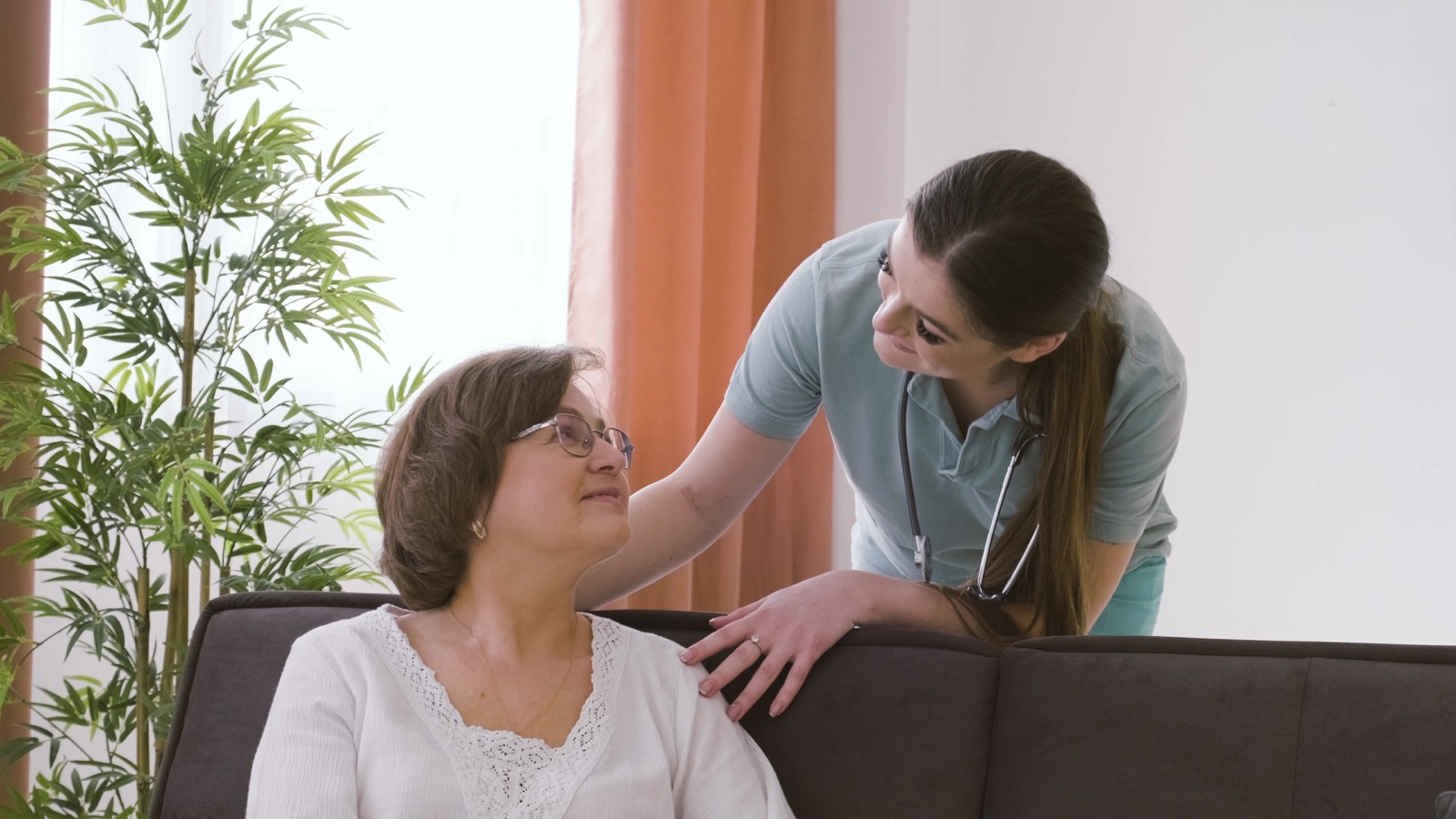 Pflegerin im Gespräch mit einer älteren Dame im Wohnzimmer
